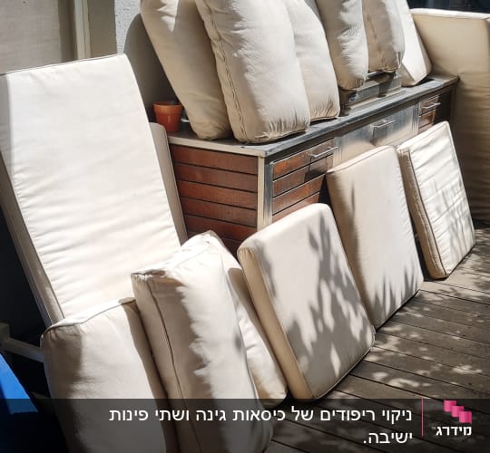 כריות ספה מונחות לייבוש בשמש על מרפסת עץ